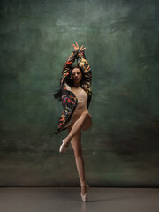 Fashionable. Graceful classic ballerina dancing on dark studio background. Bright coat. The grace, artist, movement, action and motion concept. Looks weightless, flexible. Fashion, style.
