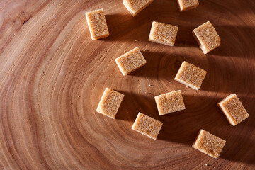 Brown cane sugar pieces on a slice, a plank of wood. With copy space.