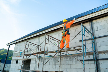 Working at height equipment,Construction worker wearing safety harness belt during working on roof structure of building on construction site.