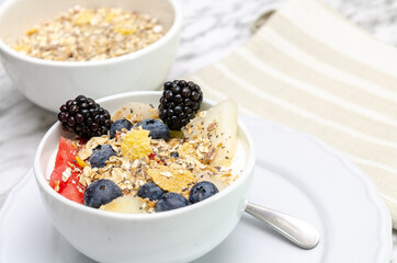 Yogurt bowl with blueberries, red berries and melon. In the background, bowl with cereals.