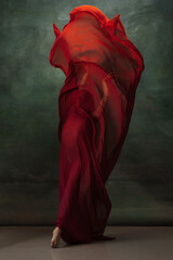 Fire flame. Graceful classic ballerina dancing on dark studio background. Deep red cloth. The...