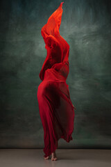 Fire flame. Graceful classic ballerina dancing on dark studio background. Deep red cloth. The grace, artist, movement, action and motion concept. Looks weightless, flexible. Fashion, style.