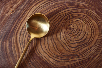 The golden spoon lies on a slice of a tree. wooden table. With copy space.