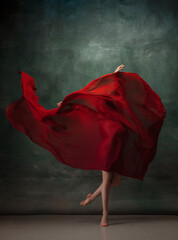 Heart beating. Graceful classic ballerina dancing on dark studio background. Deep red cloth. The...