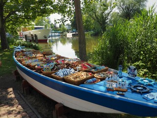 Balatonm&aacute;riaf&uuml;rdő, Hungary - June 26, 2020: Souvenirs unloaded on a blue wooden boat of a vendor at a canal of the southern shore of the lake Balaton
