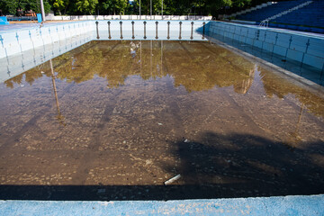 Damaged swimming pool. Old swimming pool with dirty water