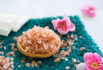 Himalayan salt aroma therapy spa set on green towel with pink flower.