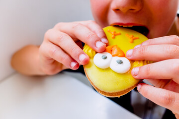 Boy bites his teeth into a cookie with icing sugar.