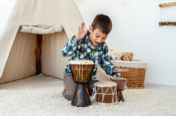 Little boy playing djembe drums indoors