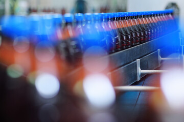 Fototapeta na wymiar Plastic beer bottles on a conveyor belt in the background of a brewery