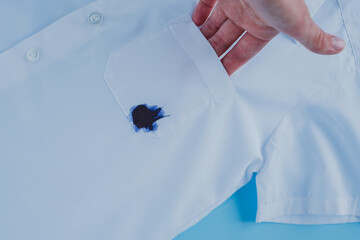 Hand holding a pocket with an ink stain on the shirt. daily life dirty stain for wash and clean...
