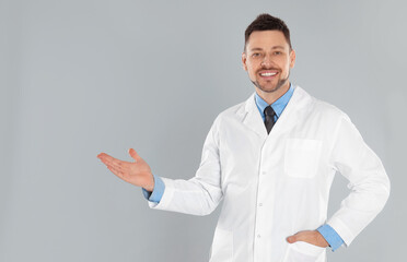 Happy man in lab coat on light grey background