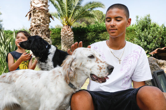Due fratelli brasiliani giocano con dei cani da caccia seduti nel giardino di una villa