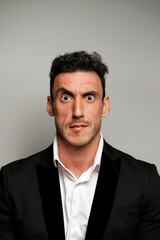 Close up portrait of a man 30-34 years old in a white shirt and a black jacket on a gray background. 