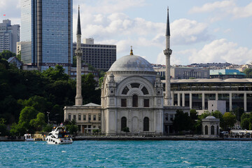 Fototapeta na wymiar A modern speedboat is seen next to the Dolmabahce mosque in a photo taken from a ferry in Bosporus strait, Istanbul, Turkey.