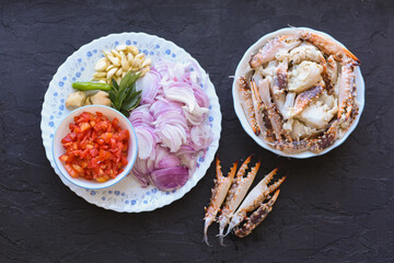 Raw fresh mud crab and ingredients for cooking Kerala crab roast curry popular hot and spicy seafood dish in India, Sri Lanka, Singapore. cooked in roasted coconut sauce. Top view on dark background.