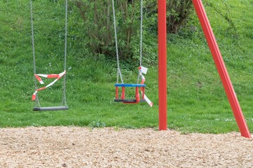 Corona virus quarantine lockdown prohibit playground swings. Closure by barrier tape. Covid-19 safety prevention action containing pandemic spread risk. Coronavirus restriction by law regulations