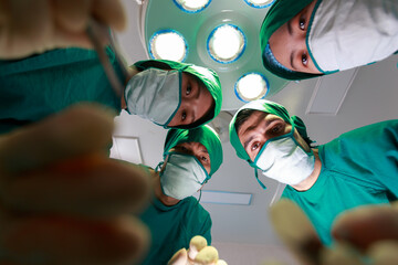 Close up four Medical Team in green suit looking down to do operation above the patient in Modern...