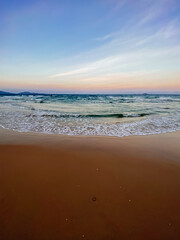 Seascape, sea view. Waves at sea, sea tide, sandy shore. Clouds in the sky. Sea sunset, colorful sky