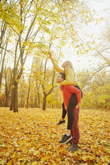 Young happy couple relaxing and loving in the autumn forest at sunset.