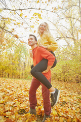 Young happy couple relaxing and loving in the autumn forest at sunset.