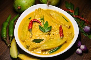 Kerala fish curry, spicy and hot king fish mango curry with green curry leaf Kerala India. Top view Barracuda Fish curry with green chili, coconut milk and mango Asian cuisine.

