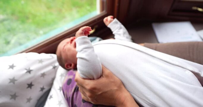 Young mother holding her baby by lthe window