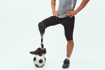 Athlete with disabilities or amputee on white studio background. Professional male football player with leg prosthesis training in studio. Disabled sport and healthy lifestyle concept. Achievements.