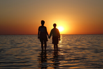 two people walk on water at sunset