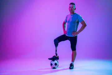 Athlete with disabilities or amputee on gradient studio background in neon. Professional male...