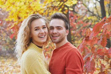 Young happy couple relaxing and loving in the autumn forest at sunset.