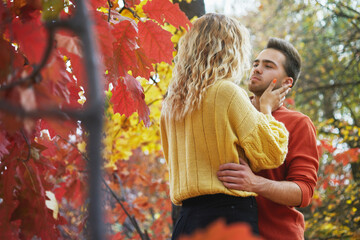 Young happy couple relaxing and loving in the autumn forest at sunset.