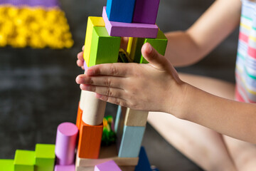 The child plays with a wooden color constructor. The multi-colored details are easy to play. Hands...