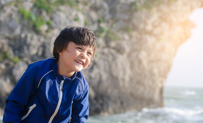 Potrait of happy kid boy smiling standing by the sea with blurry background, Chid playing in the Durdle Door beach in the weekend, Shot in Dorset, England, United Kingdom