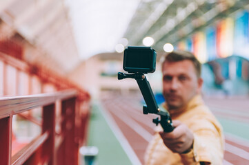 Blogger in the stadium shoots video with action camera.