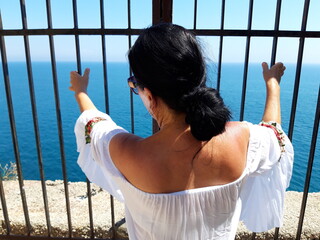 Kobieta w białej sukience na tle błękitnego krajobrazu, Gaeta, Italia.