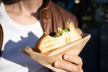 Fast food sandwich toast  in the hands of a guy, bitten off. Snack on the street