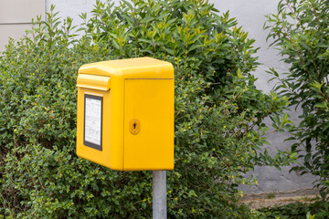 Briefkasten am Straßenrand vor einer Hecke