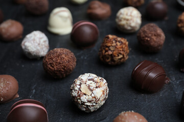 Obraz na płótnie Canvas Different delicious chocolate candies on black table, closeup