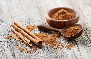 Cinnamon powder with cinnamon bark on wooden background