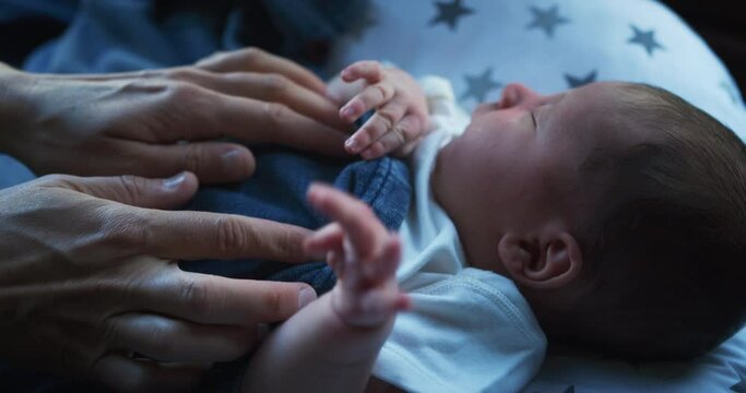 Hands of mother comforting baby on a cushion by window