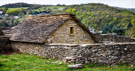 old rural house on a hill build from rocks on a hill with a wall