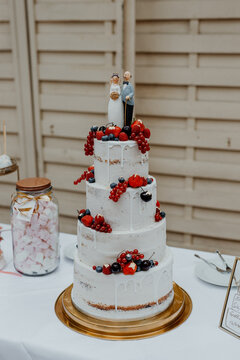 Sommerliche Hochzeitstorte mit Beeren und altem Brautpaar als Figur 