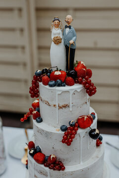 Sommerliche Hochzeitstorte mit Beeren und altem Brautpaar als Figur 