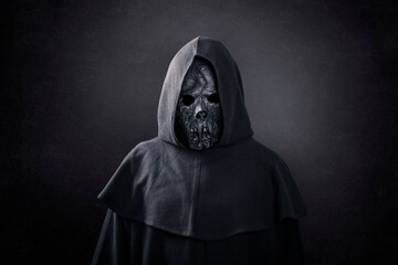 Scary figure in hooded cloak in the dark