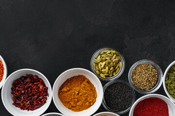 Bowls with assorted spices on dark background