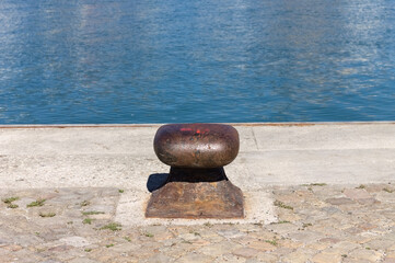 Isolated rusted mooring bollard on the jetty of a commercial dock (Pesaro, Italy, Europe)