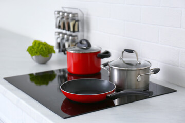 Saucepots and frying pan on induction stove in kitchen