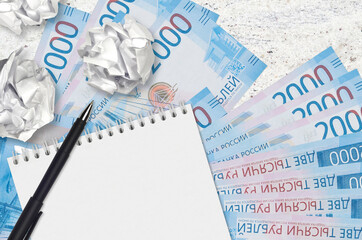 2000 russian rubles bills and balls of crumpled paper with blank notepad. Bad ideas or less of...