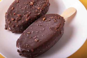 tasty cold chocolate ice cream with nuts pieces on wooden stick